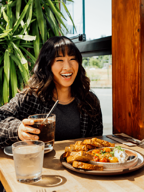 asian girl wearing black who is really happy to eat a meal at moxies, one of northland properties' restaurant brands