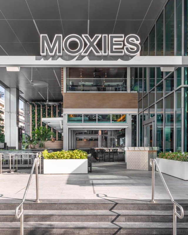 asian girl wearing black who is really happy to eat a meal at moxies, one of northland properties' restaurant brands